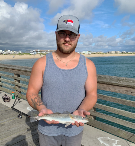 Man holding a fish standing on Jennette's Pier in Nags Head, NC
