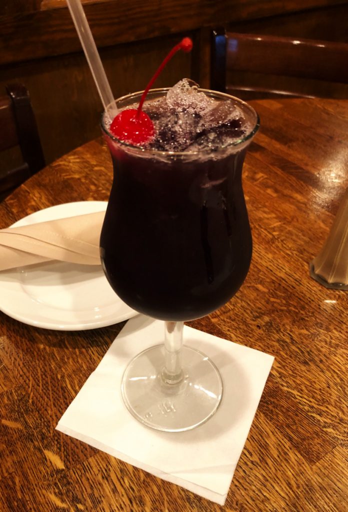 dark drink with cherry garnish and a straw